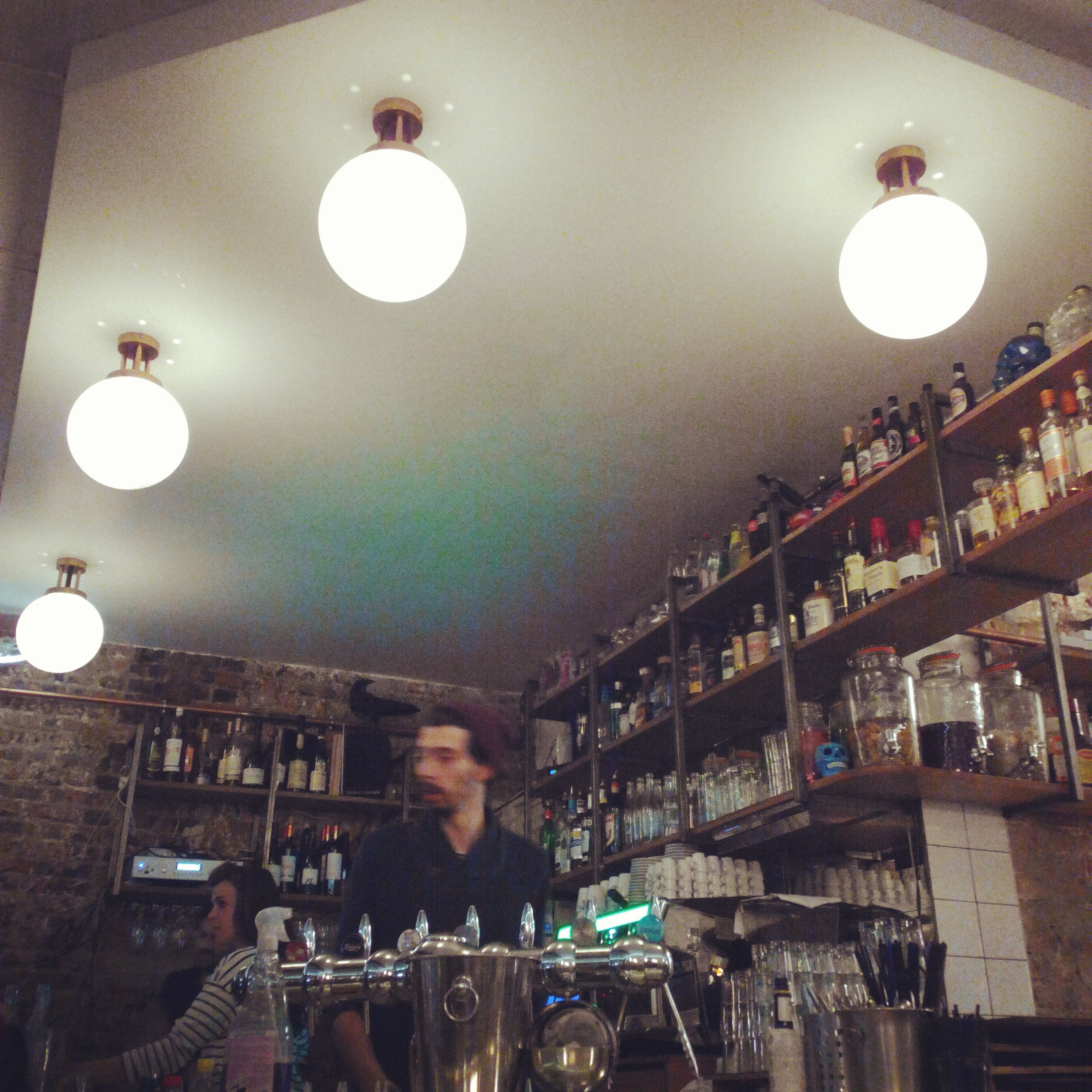 A bartender behind the counter at Triplettes Bar, Paris, France